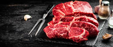 Pieces of raw beef on a stone board. On a black background. High quality photo