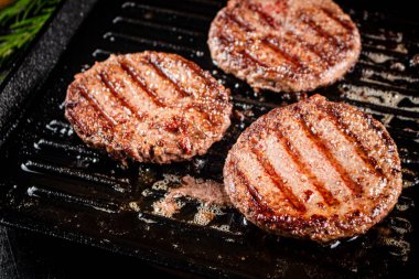 Grilled burger in a frying pan. On a black background. High quality photo