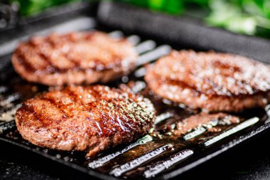 Grilled burger in a frying pan. On a black background. High quality photo