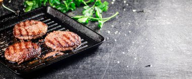 Cooking a delicious grilled burger on a pan with oil bubbles. On a black background. High quality photo