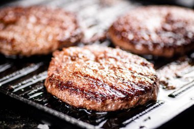 Grilled burger in a frying pan. On a black background. High quality photo