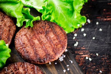 Fragrant grilled burger with greens. Against a dark background. High quality photo