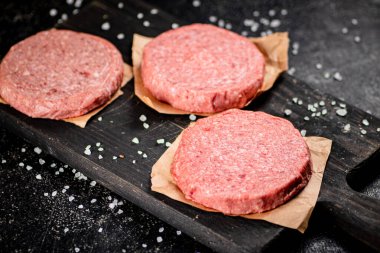 Raw burger on a cutting board. On a black background. High quality photo