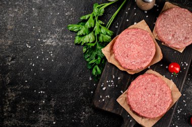 Raw burger on a cutting board. On a black background. High quality photo