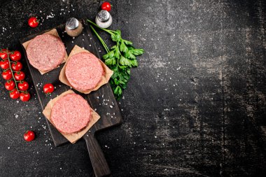 Raw burger on a cutting board. On a black background. High quality photo