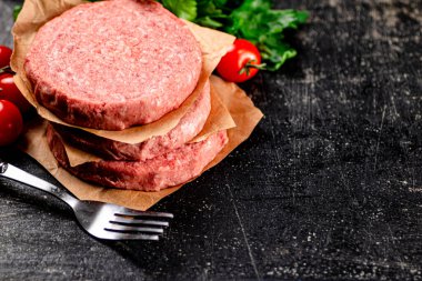 Raw burger with tomatoes and parsley. On a rustic background. High quality photo