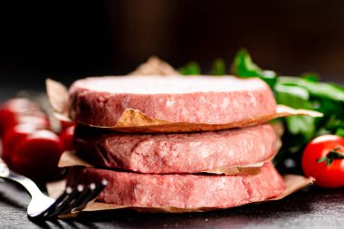 Raw burger with tomatoes and parsley. On a rustic background. High quality photo