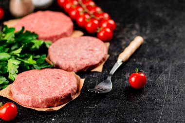 Raw burger with tomatoes and parsley. On a rustic background. High quality photo