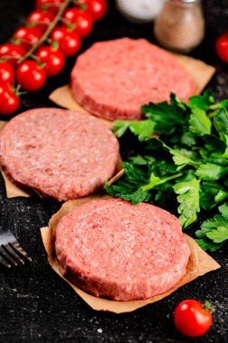 Raw burger with tomatoes and parsley. On a rustic background. High quality photo