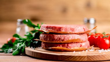 Raw burger with fresh tomatoes. On a wooden background. High quality photo