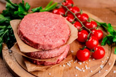 Raw burger with fresh tomatoes. On a wooden background. High quality photo
