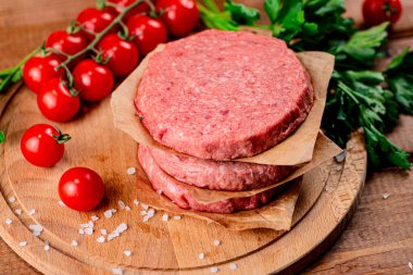 Raw burger with fresh tomatoes. On a wooden background. High quality photo