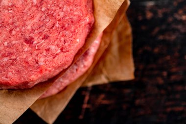 Raw burger on paper. On a rustic dark background. High quality photo