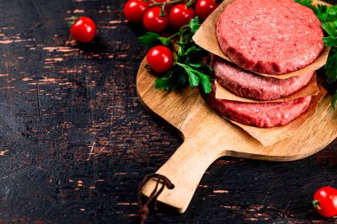 Raw burger with tomatoes and parsley. Against a dark background. High quality photo