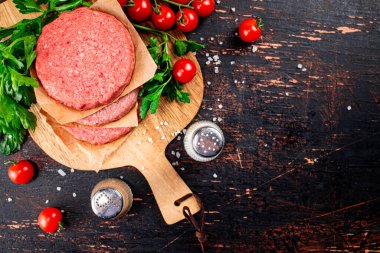 Raw burger with tomatoes and parsley. Against a dark background. High quality photo