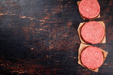 Raw burger on paper. On a rustic dark background. High quality photo