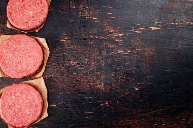 Raw burger on paper. On a rustic dark background. High quality photo