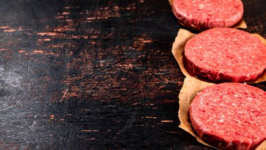 Raw burger on paper. On a rustic dark background. High quality photo