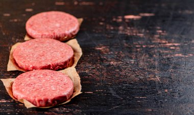 Raw burger on paper. On a rustic dark background. High quality photo