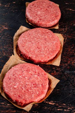 Raw burger on paper. On a rustic dark background. High quality photo
