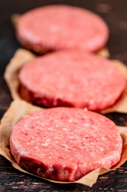 Raw burger on paper. On a rustic dark background. High quality photo