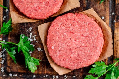 Raw burger on a cutting board with parsley and salt. Macro background. High quality photo