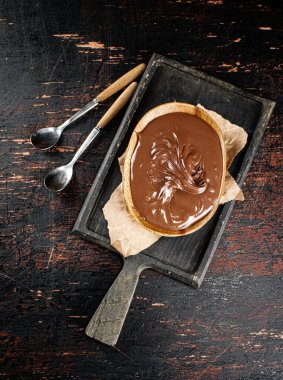 Hazelnut butter in a plate on a cutting board with paper. Against a dark background. Top view. High quality photo