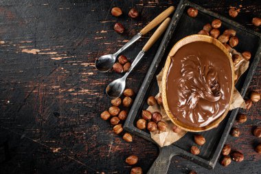 Hazelnut butter in a plate on a cutting board with paper. Against a dark background. Top view. High quality photo