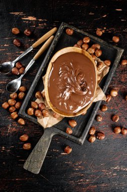 Hazelnut butter in a plate on a cutting board with paper. Against a dark background. Top view. High quality photo