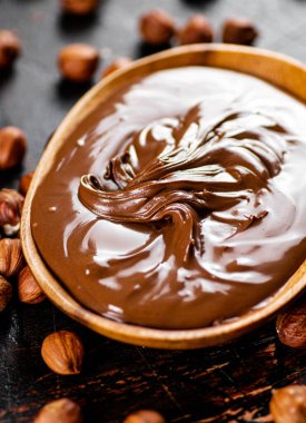 Hazelnut butter with peeled hazelnuts on the table. On a rustic dark background. High quality photo