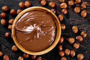 Hazelnut butter with peeled hazelnuts on the table. On a rustic dark background. High quality photo
