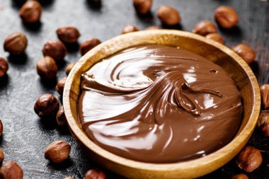 Hazelnut butter with peeled hazelnuts on the table. On a rustic dark background. High quality photo