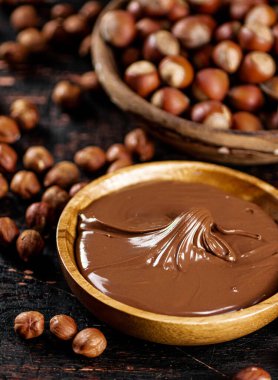 Hazelnut butter and inshell hazelnuts on the table in plates. Against a dark background. High quality photo