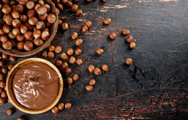 Hazelnut butter and inshell hazelnuts on the table in plates. Against a dark background. High quality photo