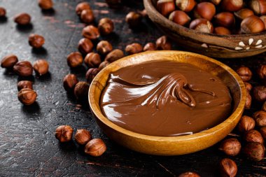Hazelnut butter and inshell hazelnuts on the table in plates. Against a dark background. High quality photo