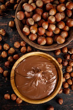 Hazelnut butter and inshell hazelnuts on the table in plates. Against a dark background. High quality photo