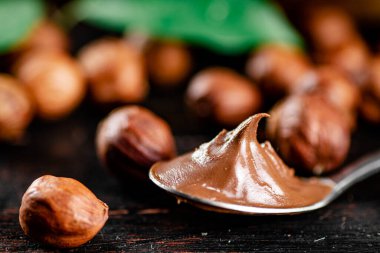 Hazelnut butter in a spoon on the table. On a rustic dark background. High quality photo