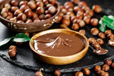 Hazelnut butter on a stone board on a plate and in a spoon. On a black background. High quality photo