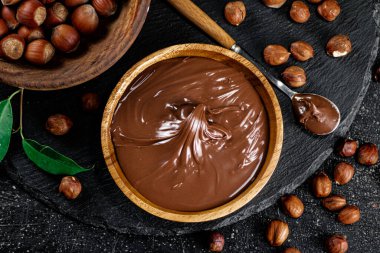 Hazelnut butter on a stone board on a plate and in a spoon. On a black background. High quality photo