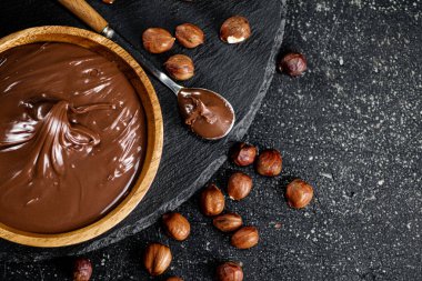 Hazelnut butter on a stone board on a plate and in a spoon. On a black background. High quality photo