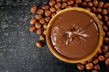 Hazelnut butter in a plate with peeled hazelnuts. On a black background. High quality photo