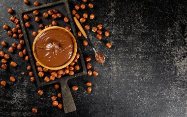 Hazelnut butter on a cutting board with a spoon. On a black background. High quality photo