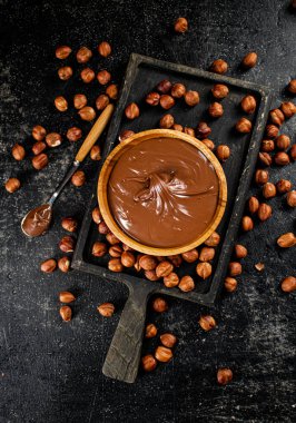 Hazelnut butter on a cutting board with a spoon. On a black background. High quality photo