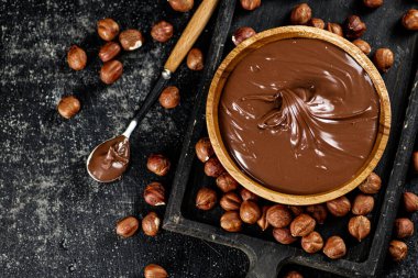 Hazelnut butter on a cutting board with a spoon. On a black background. High quality photo