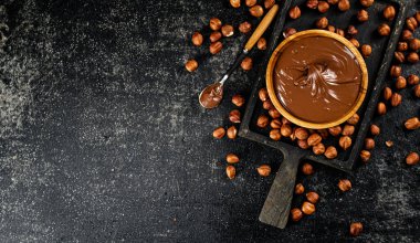 Hazelnut butter on a cutting board with a spoon. On a black background. High quality photo