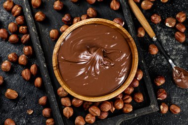 Hazelnut butter on a cutting board with a spoon. On a black background. High quality photo