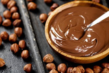 Hazelnut butter on a cutting board with a spoon. On a black background. High quality photo