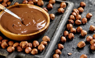 Hazelnut butter on a cutting board with a spoon. On a black background. High quality photo