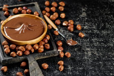 Hazelnut butter on a cutting board with a spoon. On a black background. High quality photo