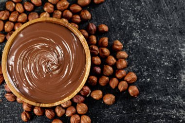 Hazelnut butter in a wooden plate. On a black background. High quality photo